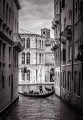 Venice in black and white, Italy. Old narrow street with lone gondola in distance. 