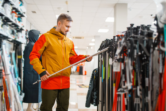 Man choosing ski poles, shopping in sports shop