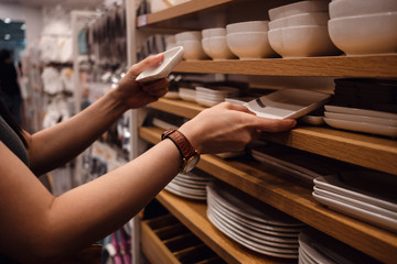Customer Compared Products from Rack in the Shop. Young Woman Choosing Dishware in Household Store. Croped image