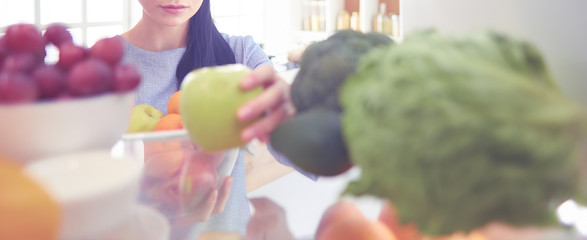 Smiling woman taking a fresh fruit out of the fridge, healthy food concept