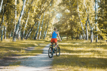 cute blonde woman cyclist cycling mountain bike on the birch forest trail