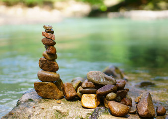 sort or stack pebble stone tower or pyramid on rock and stream water for balance training and...