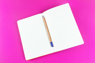 An open notebook and a pencil on a bright pink background. Place for text. The concept of learning, sketch, writing. Flat lay, minimalism, top view, design.