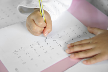 hand of child or student holding pencil and study with learning writing number and practice...
