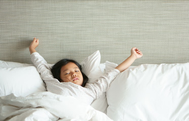 Asian child cute relax or kid girl sleep and wake up with stretch oneself and sleepy for refreshing...