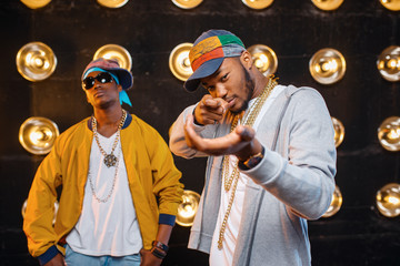Two black rappers in caps, artists on stage