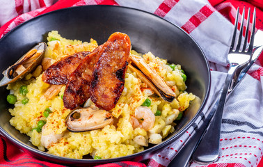 A serving of seafood paella on a table with red and white napkins