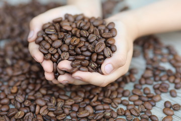 Brown coffe beans in hands, on the wooden  table, roasted arabica