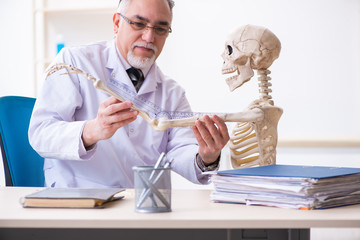 Aged male doctor with skeleton 
