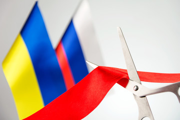 Ribbon cutting ceremony. Scissors cut red ribbon. .Russia and Ukraine flag bluered on the background. start of a partnership concept