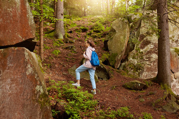 Naklejka na ściany i meble Outdoor shot of wandering energetic female, going on top of forest hill, having holidays, spending time in summer forest, being fond of nature, choosing right path to move. Wanderlust concept.