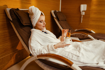 Sexy girl relaxing with cup of coffee in spa chair