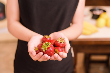 Young vegetarian girl holds a delicious, appetizing red strawberry in her hands