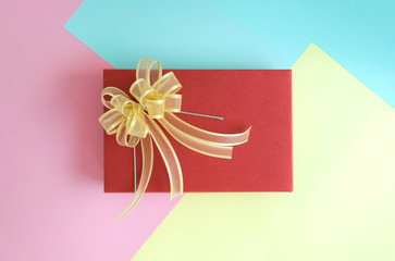 Flat lay of minimal red gift box with ribbon on the colourful background