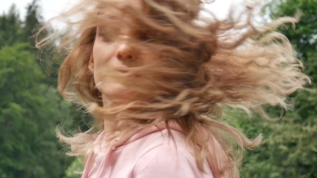 Beautiful smiling girl with long curly hair outdoor. The woman turns and makes a surprised face. Emotion of amazement, unexpected surprise
