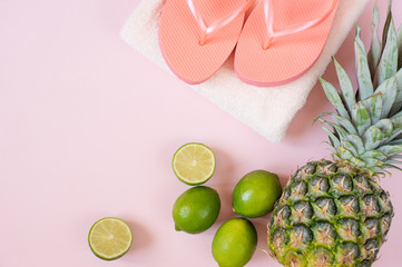 Summer composition. Tropical fruits and beach accessories - pineapple, coconut, lime, towel, flip-flops on pastel pink background. Summer concept. Flat lay, top view, copy space