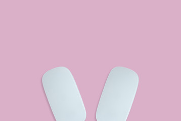 Minimal concept of two white computer mouse on the pink background as a ear rabbit