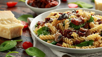 Fusilli Pasta with sun dried tomatoes, mushrooms, parmesan cheese and spinach. healthy food. - obrazy, fototapety, plakaty