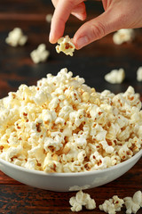 Hand takes salty popcorn from the bowl