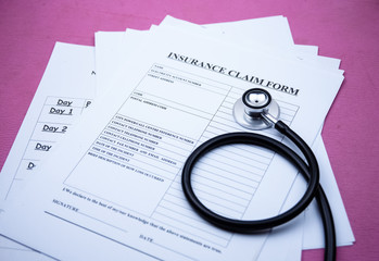 The stethoscope put beside insurance claim form,on background,blurry light around