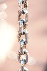 shiny metal chain on abstract blurred background. stretched metal chain with symmetrical rings vertical lines. design decoration in grunge style.  soft focus
