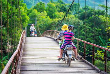 Vietnamese woman riding a bicycle on the bridge through a rural in Vietnam