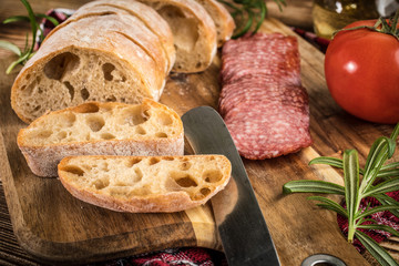 Italian ciabatta bread cut in slices with salami.