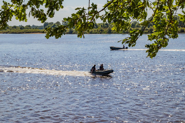 Anglers go motorboat on a river looking for fish on a sunny summer day