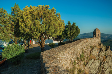 Small watchtower and stone wall over cliff with little wooden square