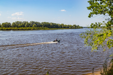 Anglers go motorboat on a river looking for fish on a sunny summer day