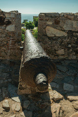 Old iron cannon aiming through crenel in wall at the Marvao Castle