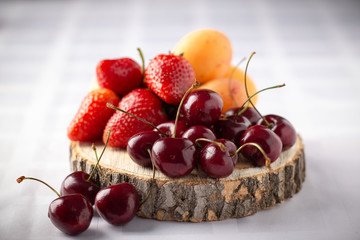 Berries cherry, Victoria and apricots on a wooden board