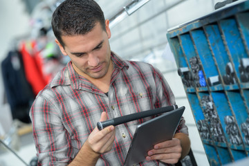man checking product on tablet in store