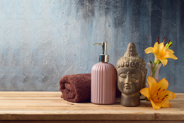 Buddha statue, flowers and towel on wooden table over dark background