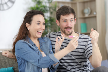 couple looking with surprised joy at pregnancy test results