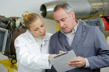 Obraz premium male and female aeronautical engineers conferring over clipboard