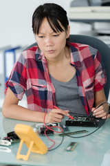 female asian computer technician using multimeter
