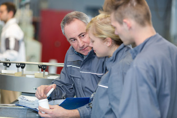 Obraz premium man showing contents of plastic pot to trainees in factory