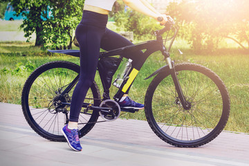 Young sporty girl riding her bike in the morning in the park, close up. Healthy lifestyle concept. Woman standing next to a bicycle