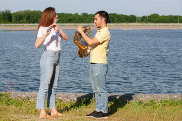 The guy playing the horn and the girl playing the flute on the lake