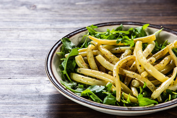 Yellow beans with arugula on wooden background