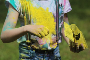 children on holiday painting each other with colours,  blue hair, yellow hair and hands on nature background
