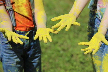 children on holiday painting each other with colours,  blue hair, yellow hair and hands on nature background
