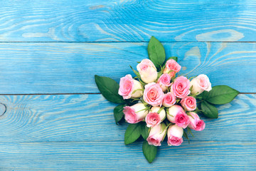 Delicate bouquet of pink roses on a blue painted wooden background. Free space for text on the left. Background, close-up, horizontal. Holiday concept.