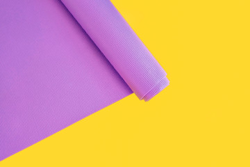 Open lilac exercise mat  on yellow background with palm leaf. Concept for practice yoga, pilates or any  physical workout .Copy space
