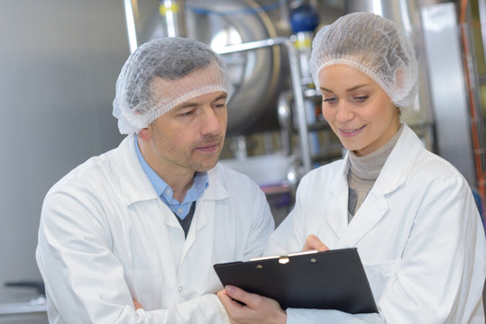 male and female quality control workers lookinf at clipboard
