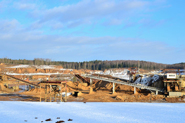 Fototapeta na wymiar Sand mining in winter conditions in an industrial quarry. Conveyor Belt in mining quarry, Mining industry. Amazing mountains against the backdrop of snow and industry
