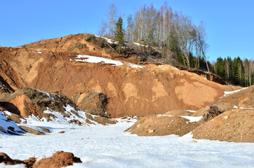 View of the small mountains in the open-pit with pines and spruces in the snow in winter. This place is located in the Belarus Minsk region, the village of Praleski, mining quarry Radashkovichi.