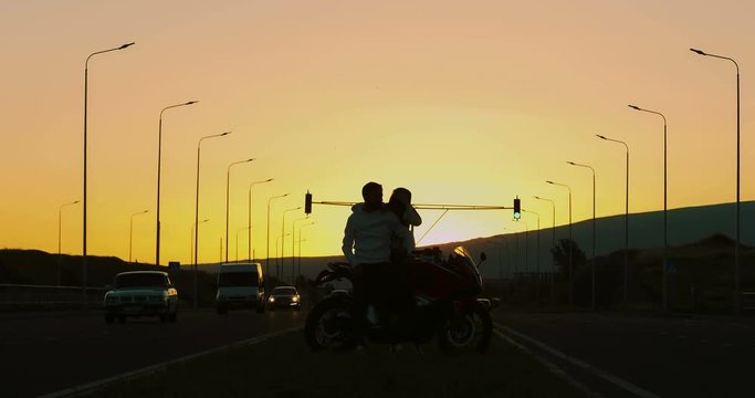couple in love standing next to a motorcycle during sunset