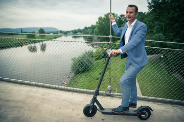 Mann genießt Aussicht mit Elektroroller auf Brücke, 